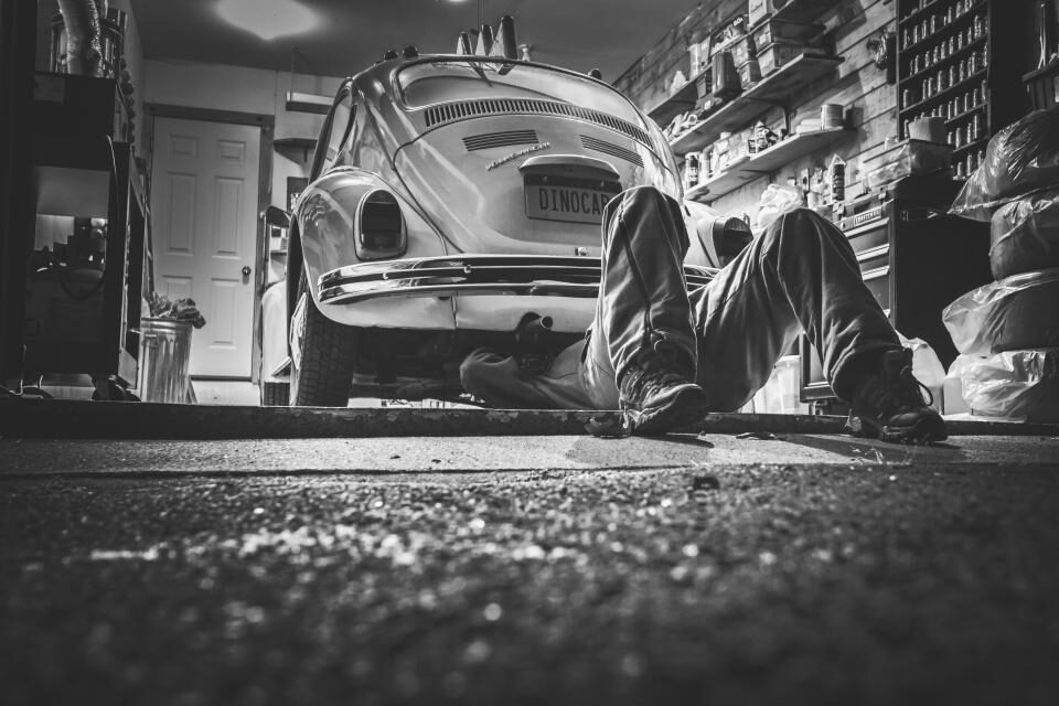 Mechanic working underneath a classic car in a workshop