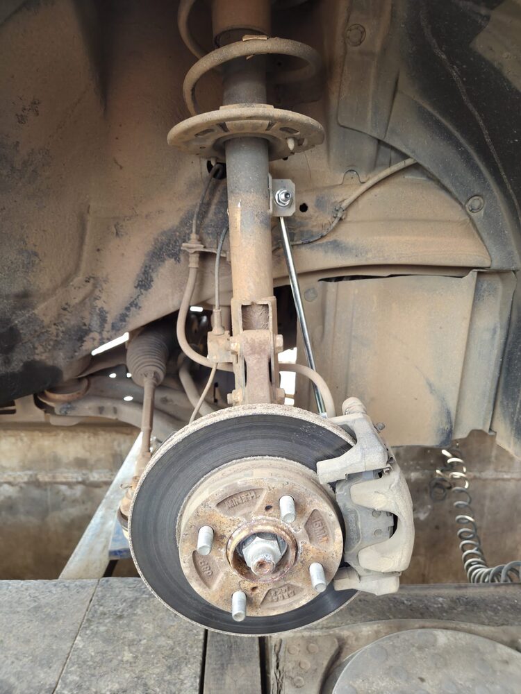 Suspension strut above a brake disc and hub